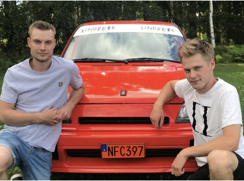 Två killar framför en röd rallybil
