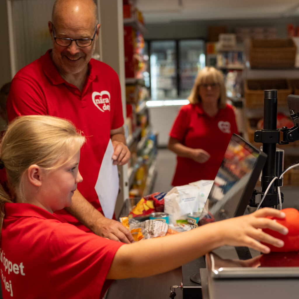 Flicka som sitter i kassan i en mataffär
